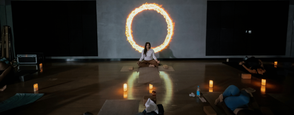 a set of people are following yoga positions of their trainer showing