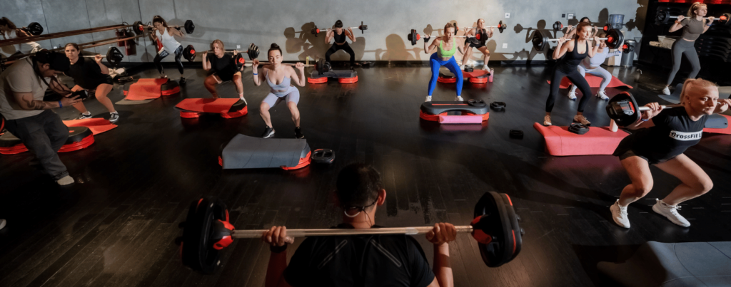 trainer is teaching a set of people to lift in les mills class